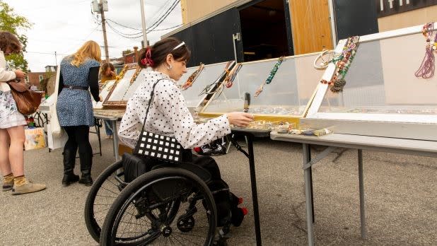 a woman in a wheelchair looks through vintage jewelry at a vendor shop at the Beacon Flea Market