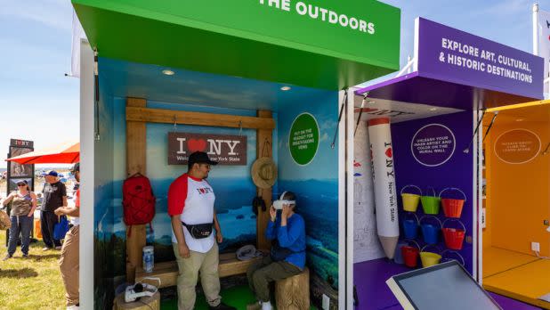 A person tries on a virtual reality headset in the outdoor adventures pod at the I LOVE NY Experience during the Bethpage Air Show