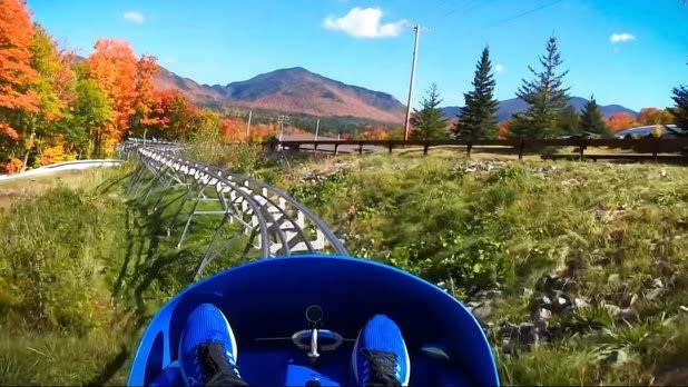 POV of a person riding through the Adirondack Mountains in peak foliage on the Cliffside Coaster at Mt. Van Hoevenberg