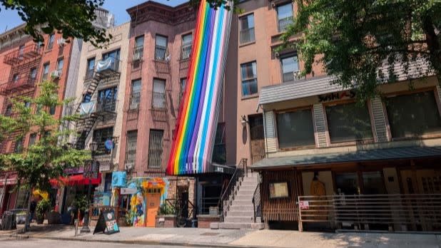 Streamers in the colors of the Pride and Trans Pride flags strung from an awning to the rooftop of a brownstone in Hell's Kitchen