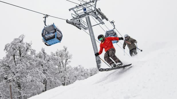 Two people ski down a slope near a chair lift at Belleayre Mountain