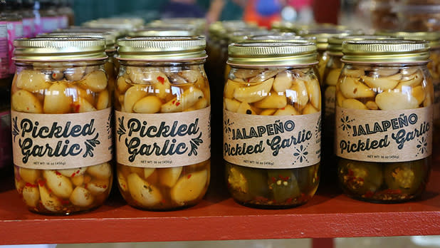 Jars of pickled garlic on a shelf at the Taste NY Marketplace at the Great New York State Fair.