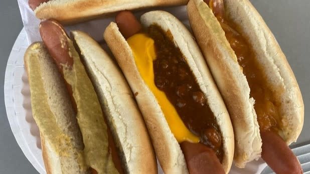 a plate of three hot dogs with various toppings