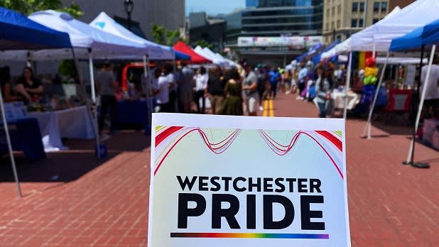 A person holds up a flyer with the title "Westchester Pride"