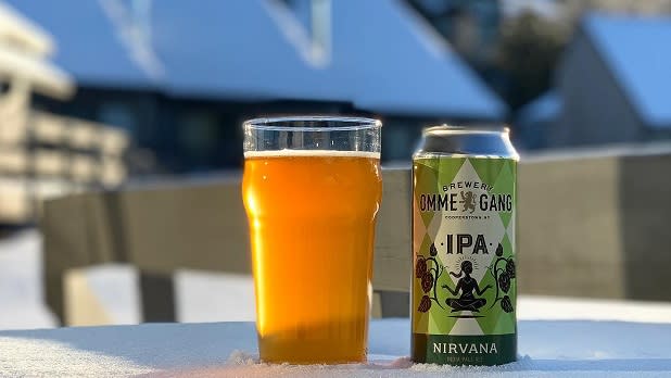 A can of Nirvana IPA stands next to a pint of beer on a snowy deck at Brewery Ommegang