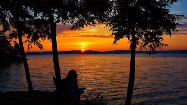 Silhouettes of trees in front of an orange sunset over the St. Lawrence River at Wellesley Island State Park