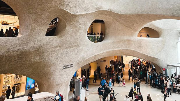 People meander through the interior of the Gilder Center's beige walls modeled after wind and water erosion
