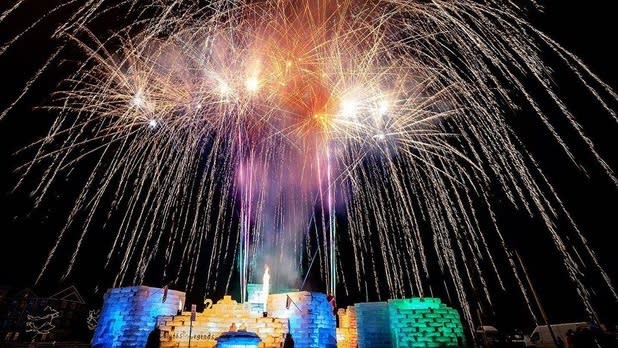 Fireworks light up the sky above a rainbow ice castle