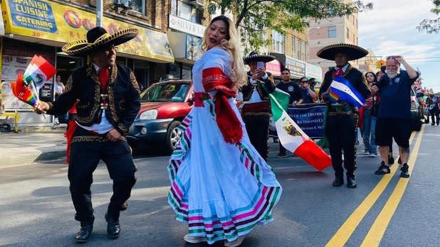 A woman and a man in traditional Mexican clothing dance in the Mexican Day Parade