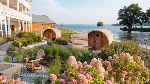 Barrel saunas stand in a serene lakeside garden at the Lake House on Canandaigua