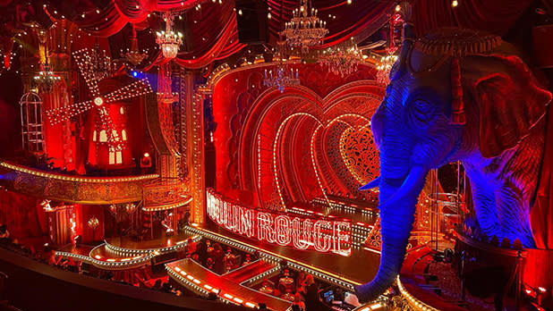 A large elephant prop borders the red-lit stage of Moulin Rouge on Broadway