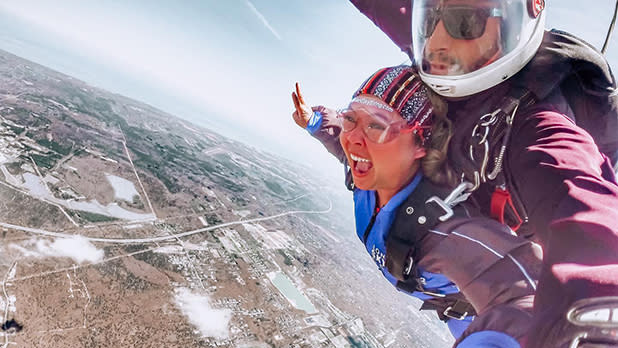 A person in a blue jumpsuit attached to a skydiving instructor skydiving over Long Island
