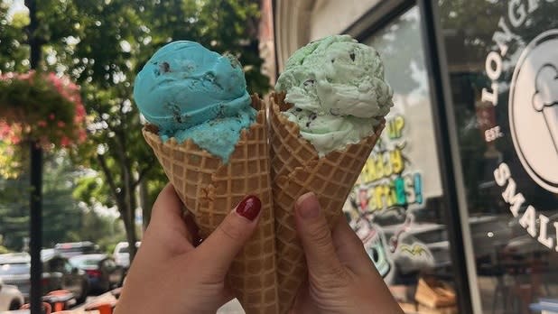 Two ice cream cones, one with mint chocolate chip and one with cookie monster ice cream, cheers-ing at Longford's