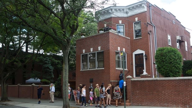 People walk into the Louis Armstrong House Museum on a tour