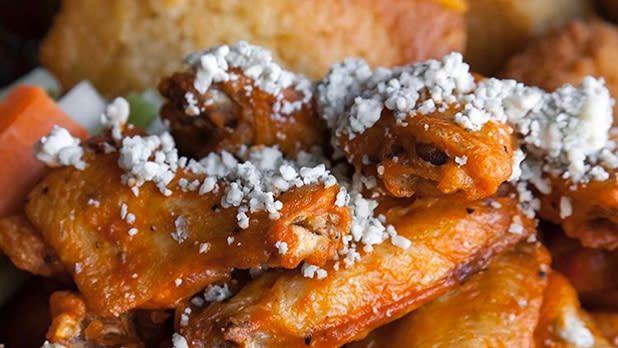 A plate of wings covered with crumbled blue cheese.