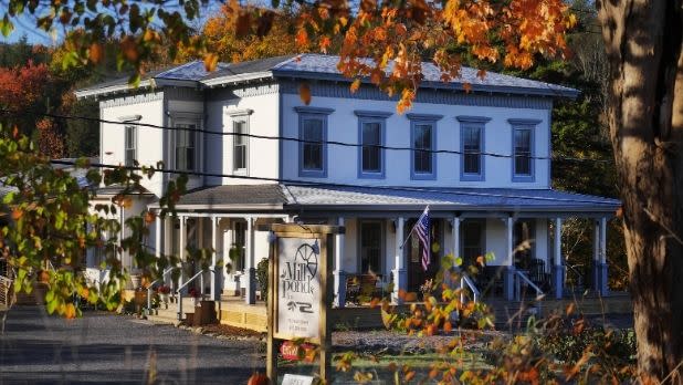 The Mill Pond Inn with sign in foreground and fall foliage