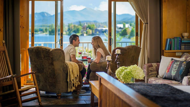 Two people looking at each other while sitting in wingback chairs facing a lake at Mirror Lake Inn