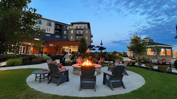 Chairs surround a lit fire pit looking towards a hotel