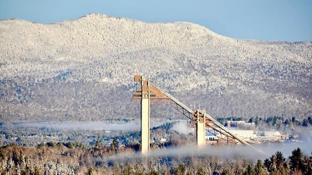 Snow-covered mountains loom behind the Olympic Ski Jumping Complex in Lake Placid
