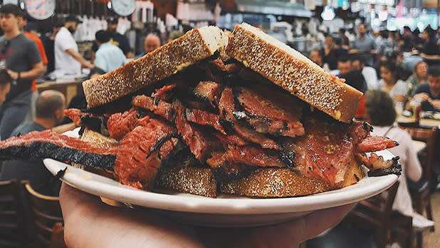 A plate topped with a pastrami sandwich on rye bread at Katz's Delicatessen