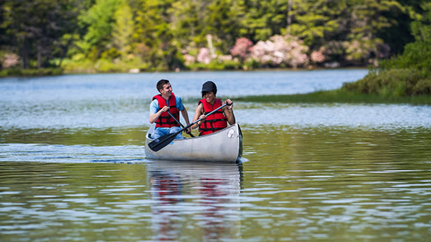A man and woman in red safety jackets canoeing along north-south lake in the Catskills