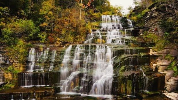 A water rushes down jagged rocks surrounded by fall colors and vegetation