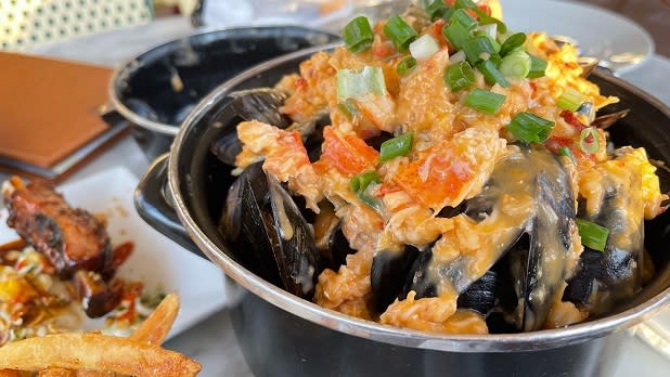 A heaping pot of mussels drenched in a creamy lobster sauce topped with freshly chopped scallions at Waterzooi in Garden City