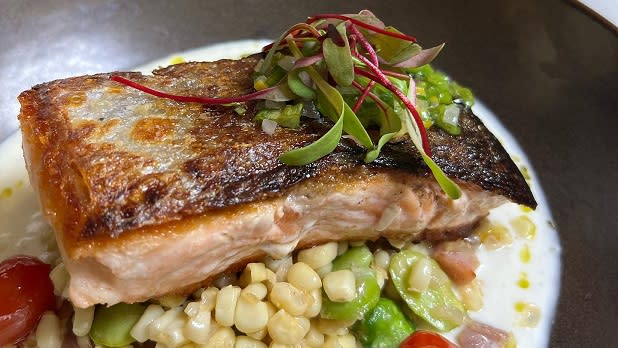 Seared salmon with white asparagus puree, corn, and fava succotash with blistered tomatoes and scallion gremolata at Prime at Saratoga National