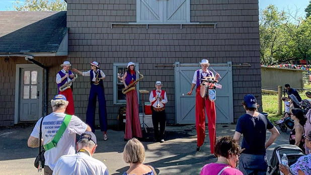 Members of a band on stilts to make them taller, playing live music at Queens County Fair.