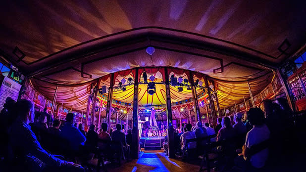 An audience watches a performer in the Spiegeltent at the Rochester Fringe Festival