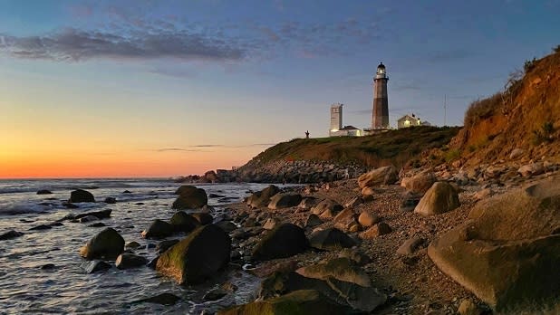 Montauk Point Lighthouse seen at dawn as the sky glows orange