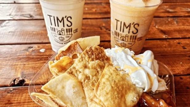 Two milkshakes behind a plate of golden nachos alongside apple pie filling, ice cream, and whipped cream.