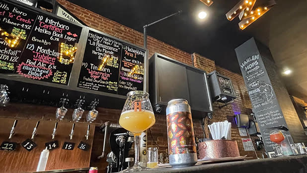 A cozy bar scene featuring a beer on the counter and a menu displayed on the wall behind it.