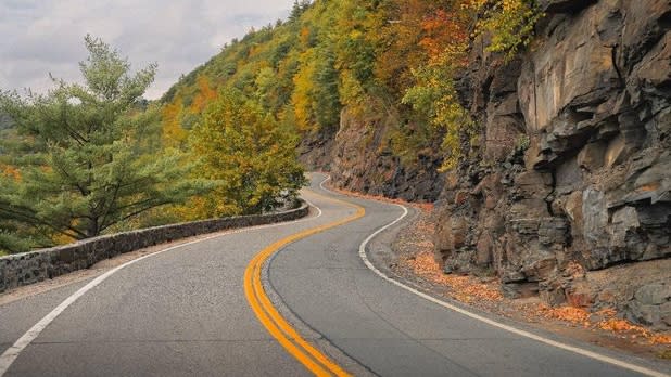 View from a car driving on the windy road of the Upper Delaware Scenic Byway surrounded by fall foliage