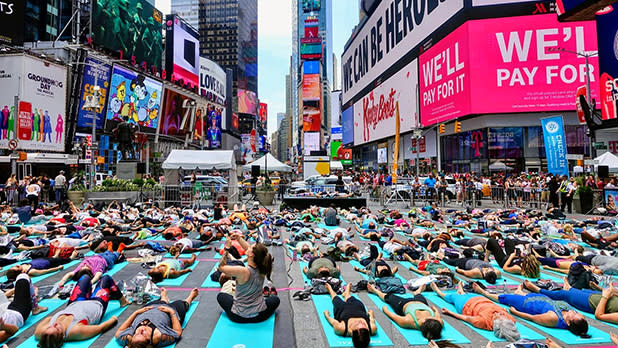 A large group of people doing yoga in Times Square in New York City.