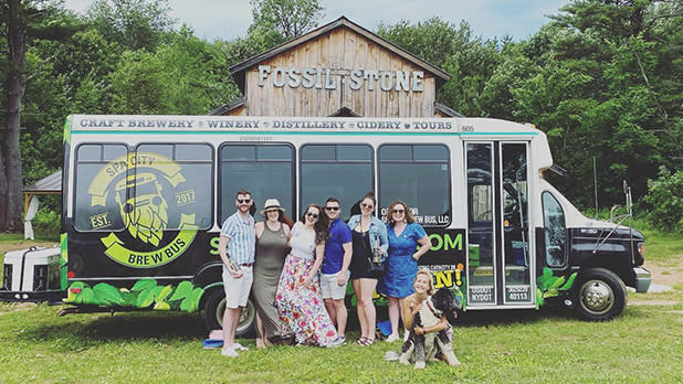 A group posing in front of Spa City Brew Bus at Fossil Stone Farms Winery