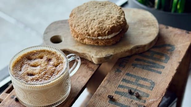 A coffee in a clear glass mug and a pastry
