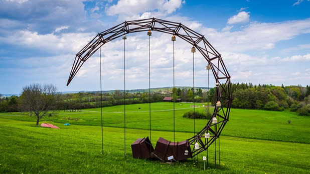 A crescent-shaped outdoor sculpture in a green field