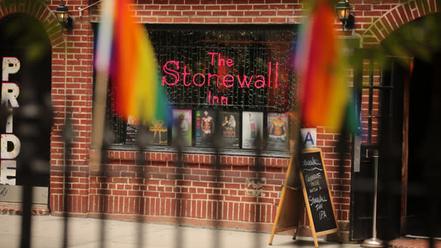 The Stonewall Inn with neon sign and Pride flags in foreground