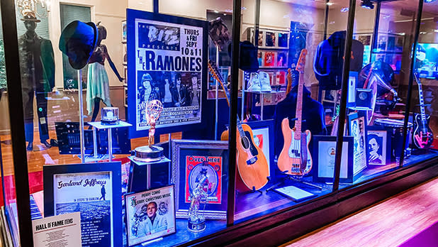 A glass case displays guitars and posters from musical artists at the Long Island Music & Entertainment Hall of Fame