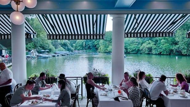 People dining at tables on the outdoor patio of the Central Park Boathouse