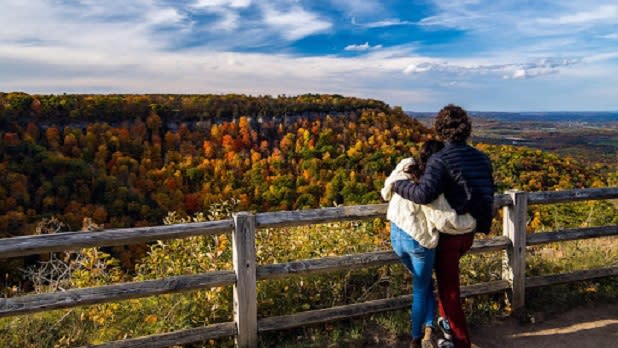 A couple hugging as they lookout at mountains decorated in fall foliage