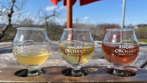 Two light ciders and one pink on a wooden flight