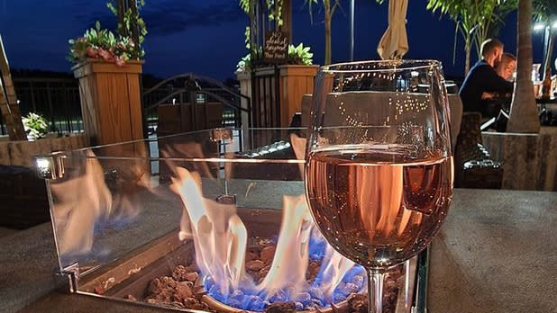 A glass of rose in front of an outdoor fire pit