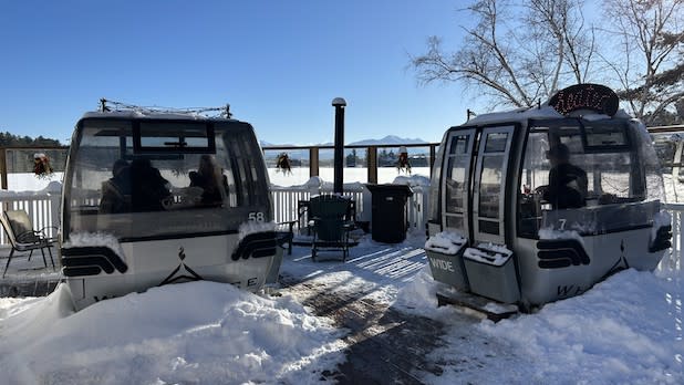 Two ski Gondola cabins sit on a snowy porch outside of The Cottage