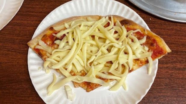 Cold mozzarella cheese sprinkled on a slice of cheese pizza