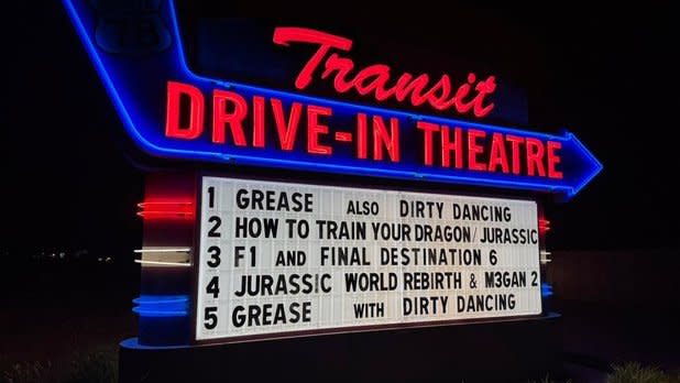 Photo of a retro, blue and red neon sign that reads "Transit Drive-in Theatre" with upcoming showings underneath
