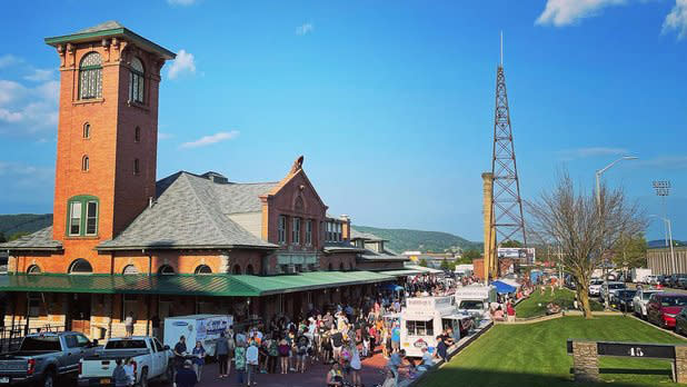 Exterior of people meandering around the tall brick building with dark green awnings of the old Lackawanna Train Station
