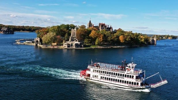 Uncle Sam Boat Tours sails along the St. Lawrence River past an island covered in fall foliage