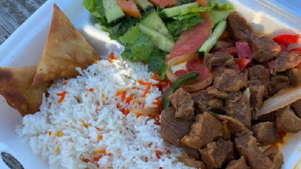 White rice, beef tips, a salad, and two chips in a to-go container